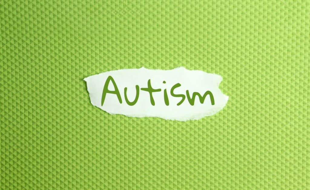 un papier déchiré avec l'inscription autisme sur un fond vert