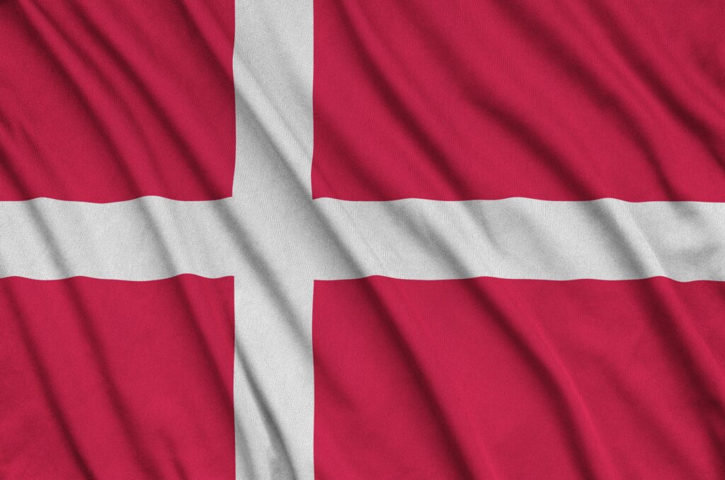 Le drapeau du Danemark est représenté sur un tissu de tissu sportif avec de nombreux plis. Équipe sportive agitant une bannière