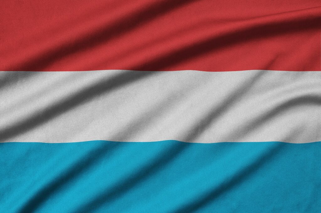 Le drapeau luxembourgeois est représenté sur une toile de sport avec de nombreux plis. Équipe sportive agitant une bannière