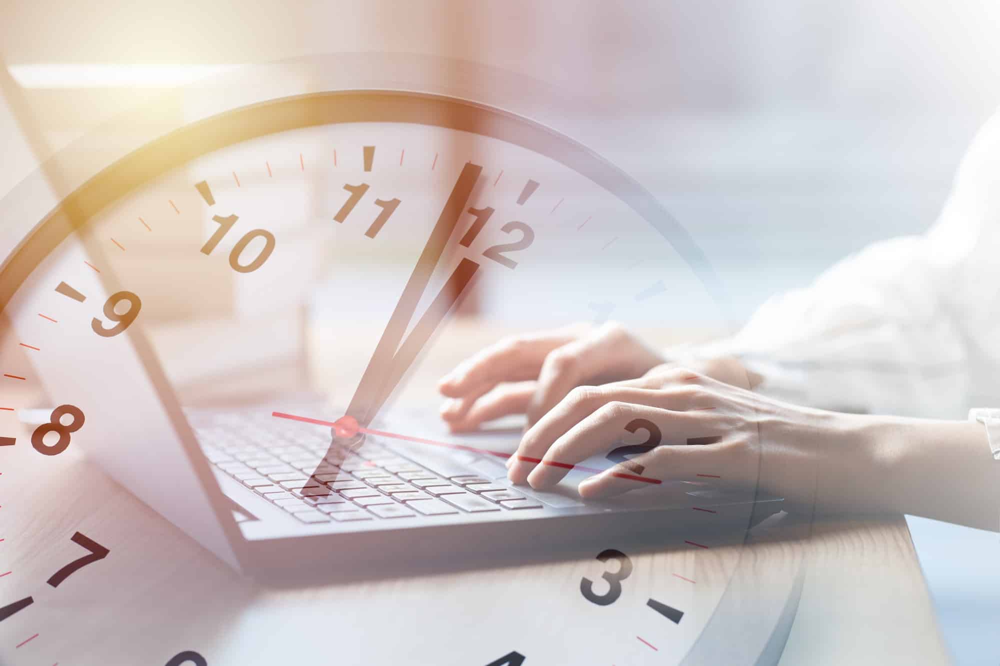 Concept de temps de travail d'une entreprise : des personnes travaillent en tapant sur un ordinateur portable avec une horloge à l'heure.