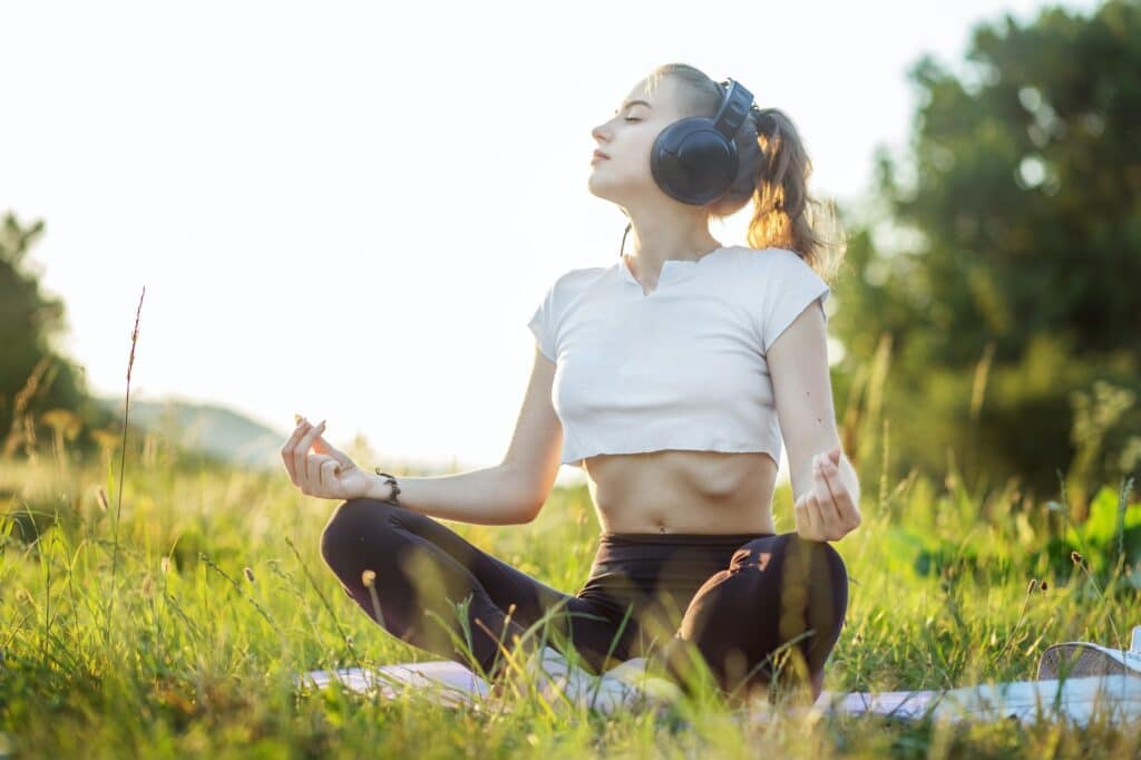 La fille écoute de la musique avec des écouteurs. Une femme est en train de méditer. Concept pour le style de vie, la musique